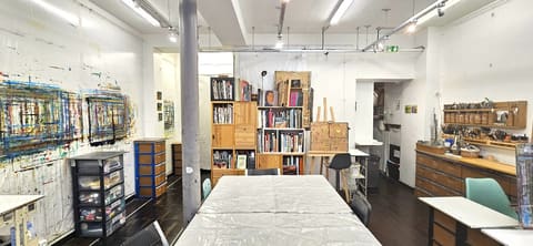 L'intérieur de l'atelier : grande table, bibliothèque et chevalet